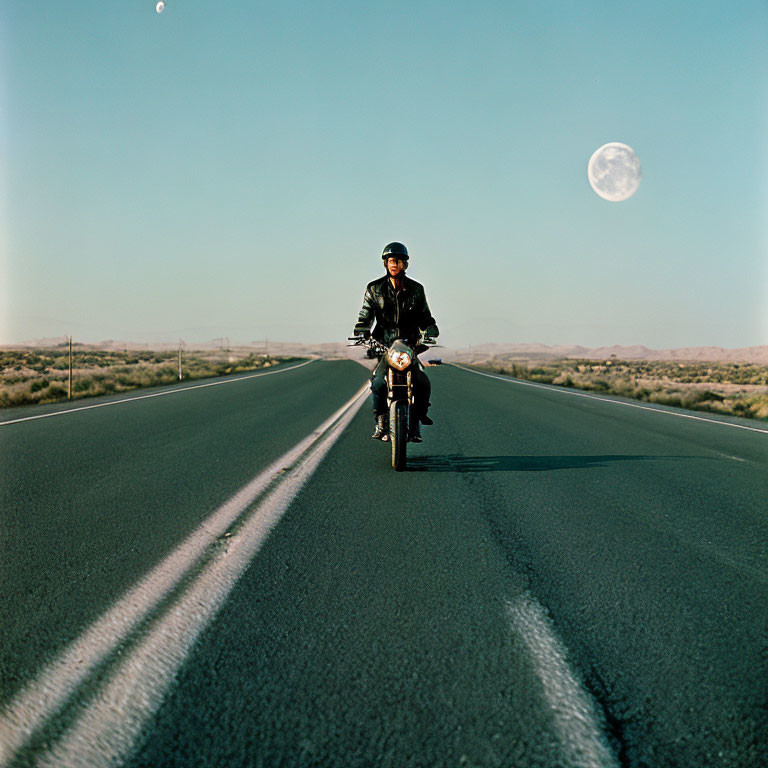 Motorcyclist riding on deserted road under daytime moon.