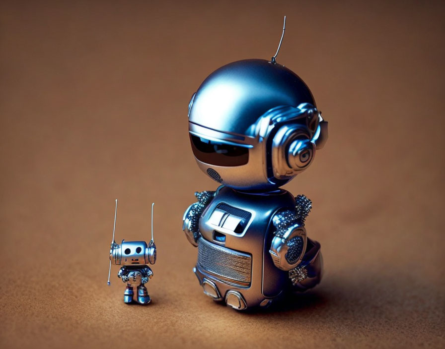 Two robots on brown surface: small intricate robot next to larger shiny robot.