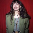 Digital artwork: Woman with long black hair, green jacket, white top, red background