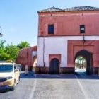 Vintage Blue Car Parked in Front of Traditional Pink Building with Palm Tree