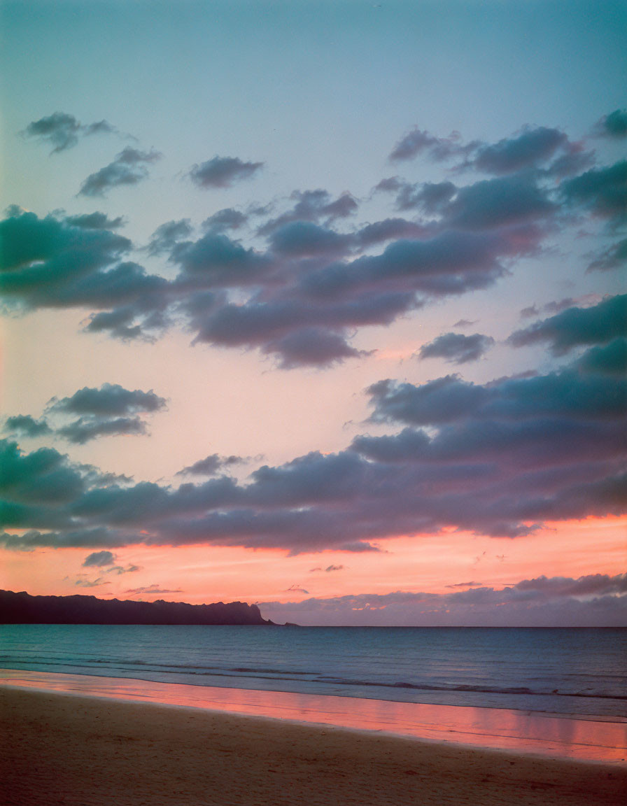 Tranquil sunset beach scene with pink sky and silhouetted coastline