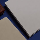 Closed brown notebook, white paper, and open beige folder on dark blue surface