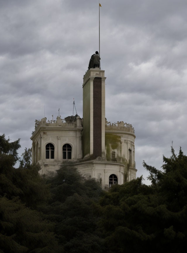 White Tower with Chimney and Flag Amid Green Foliage Under Cloudy Sky