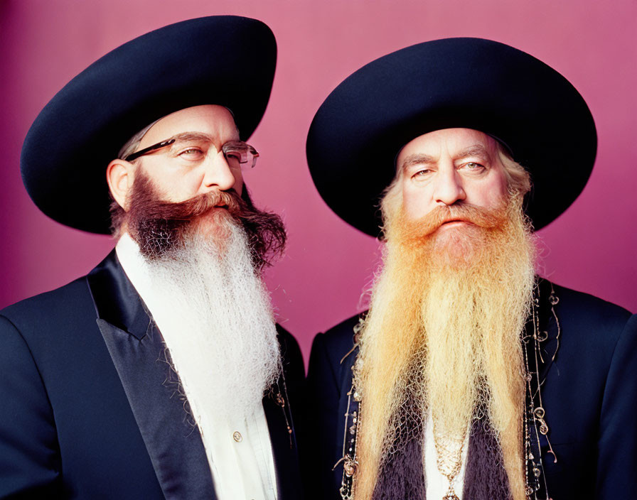 Men with long beards in traditional hats and coats on pink background