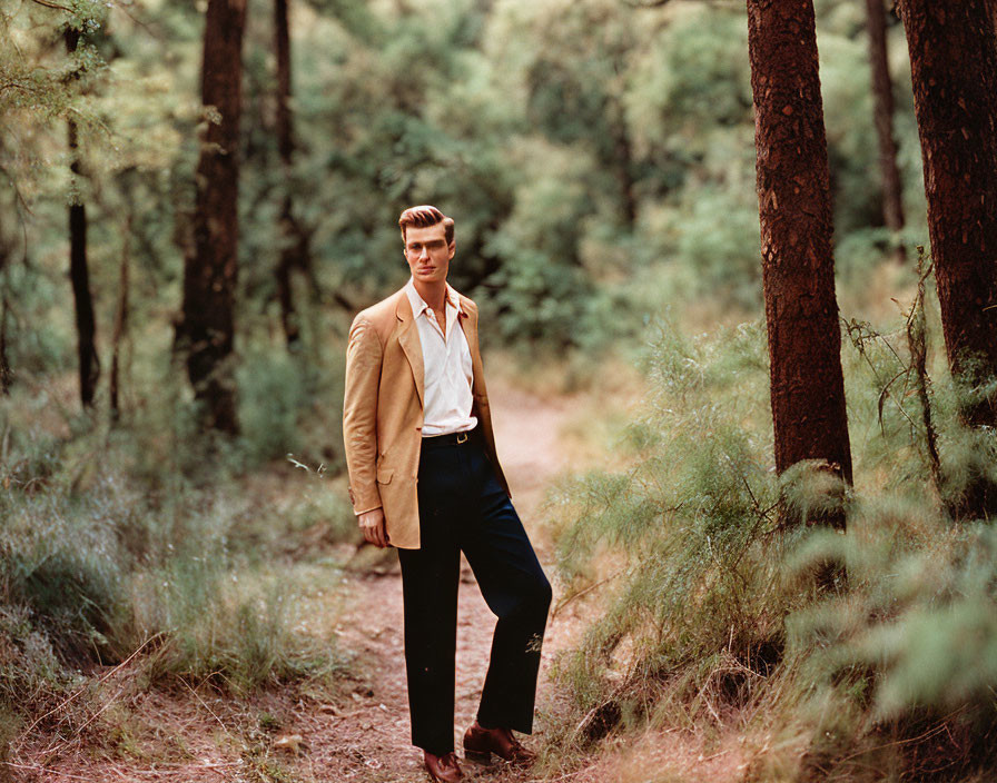 Stylish man in tan jacket on forest path with focused expression