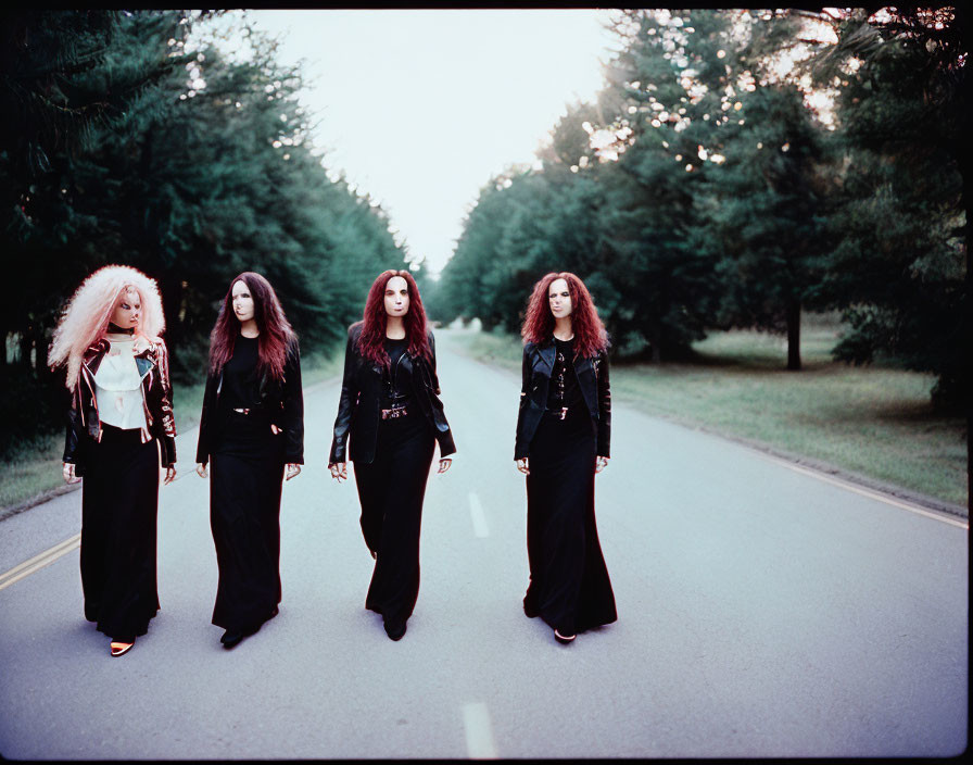 Four women with voluminous hair walking on deserted road with trees