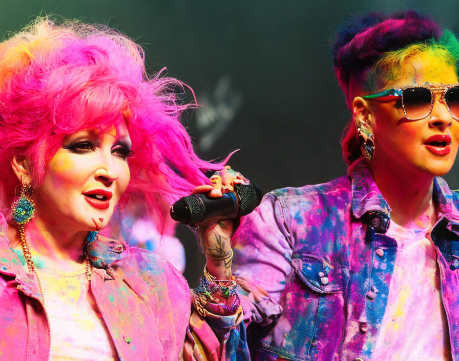 Vibrantly dressed individuals singing on stage with colorful hair