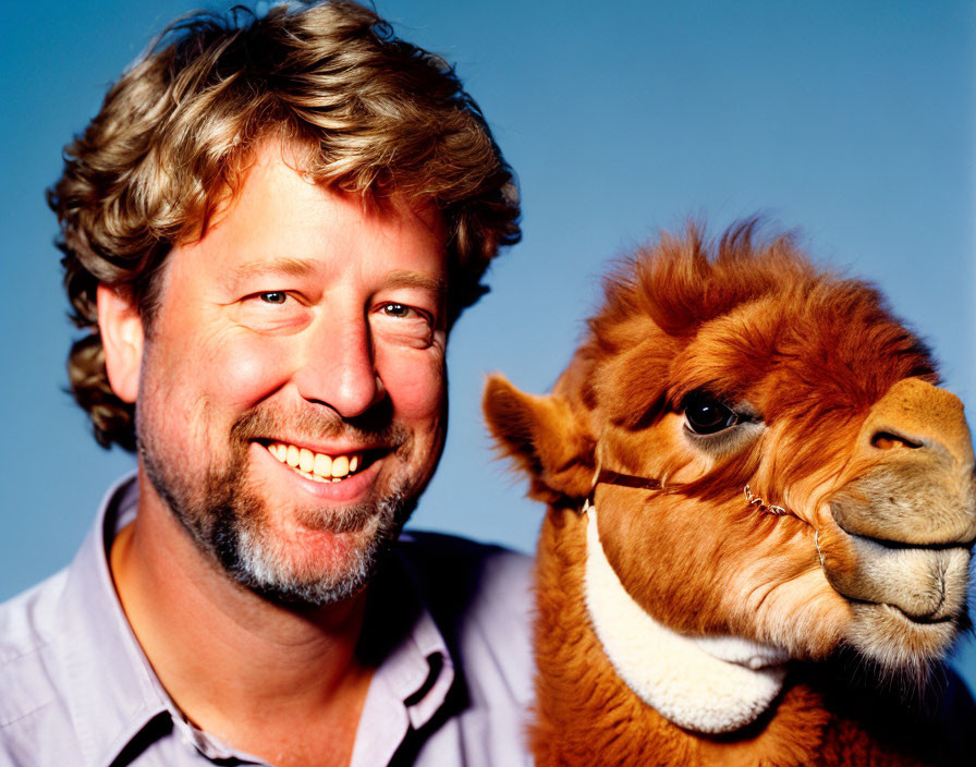 Smiling man with camel on blue background