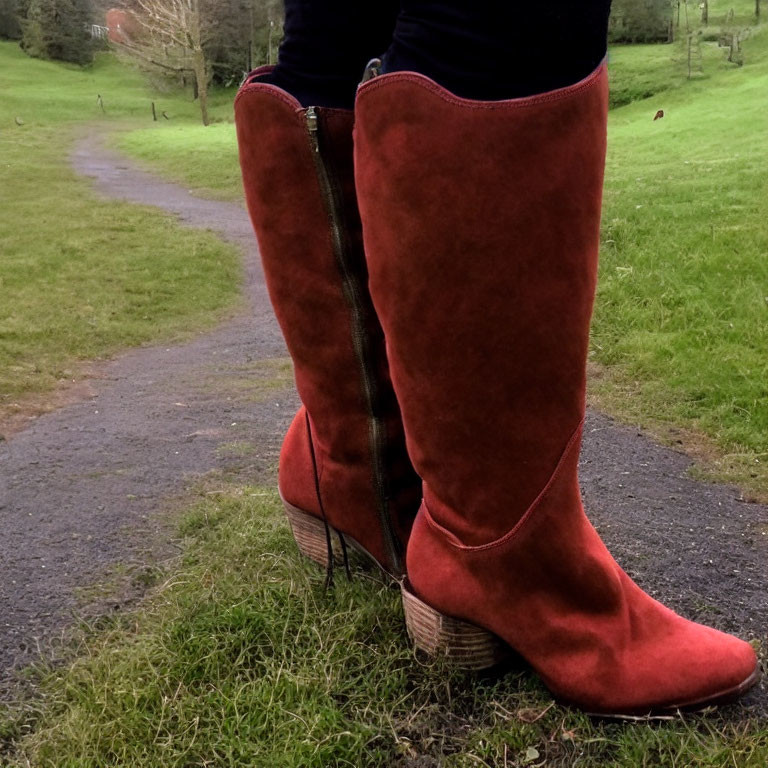 Person in Red Suede Knee-High Boots on Grass Path