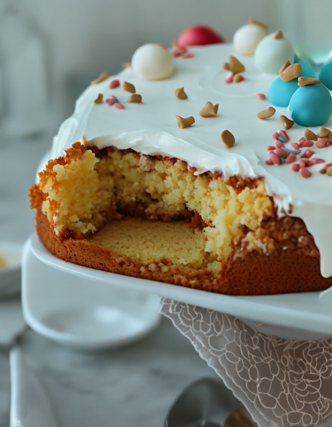 Frosted cake with multicolored eggs and sprinkles on white stand