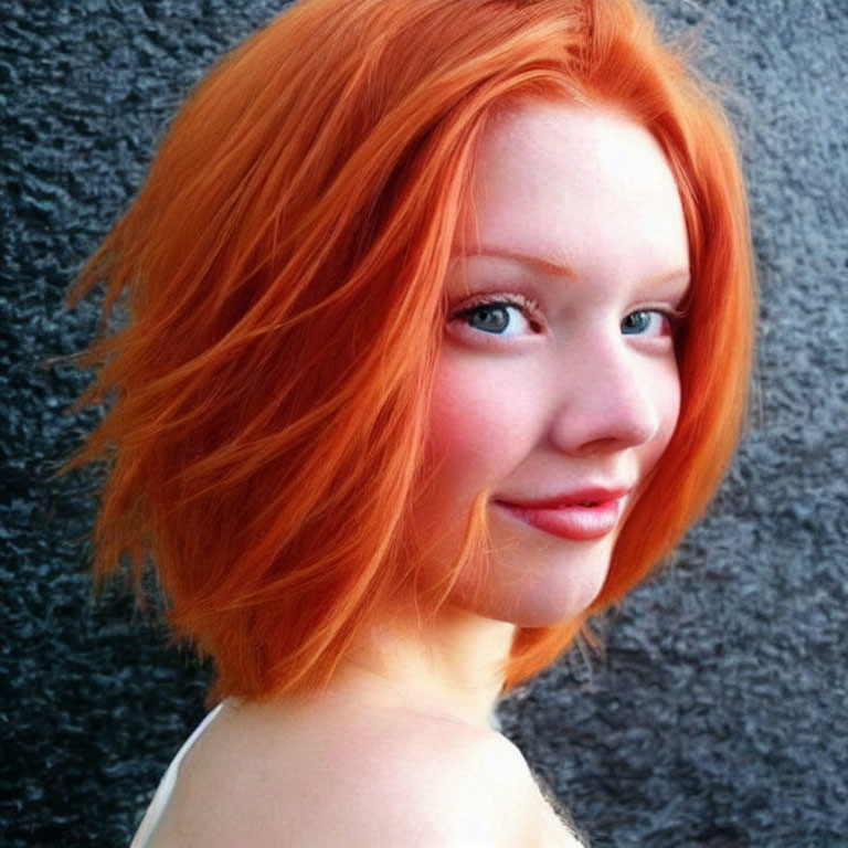 Vibrant red hair and fair skin person smiling on textured gray background