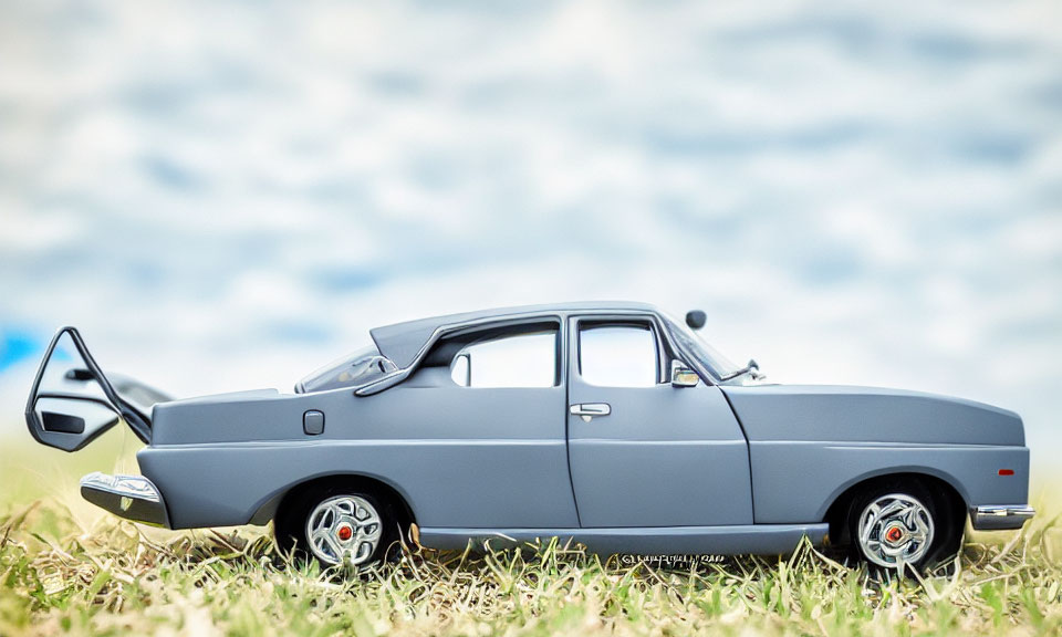 Classic Car Scale Model with Open Door on Grass Under Cloudy Sky