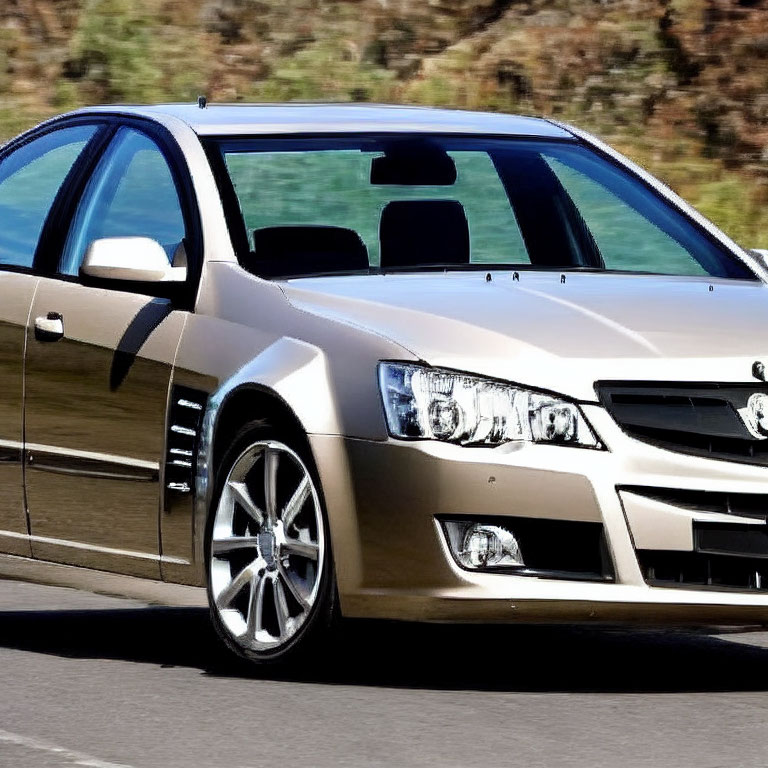 Metallic Beige Sedan in Motion on Asphalt Road with Grille, Alloy Wheels, and Head