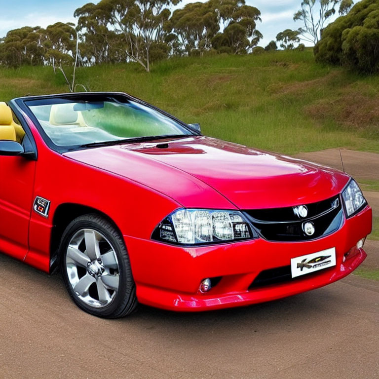 Convertible Sports Car Parked with Headlights On Near Roadside Greenery