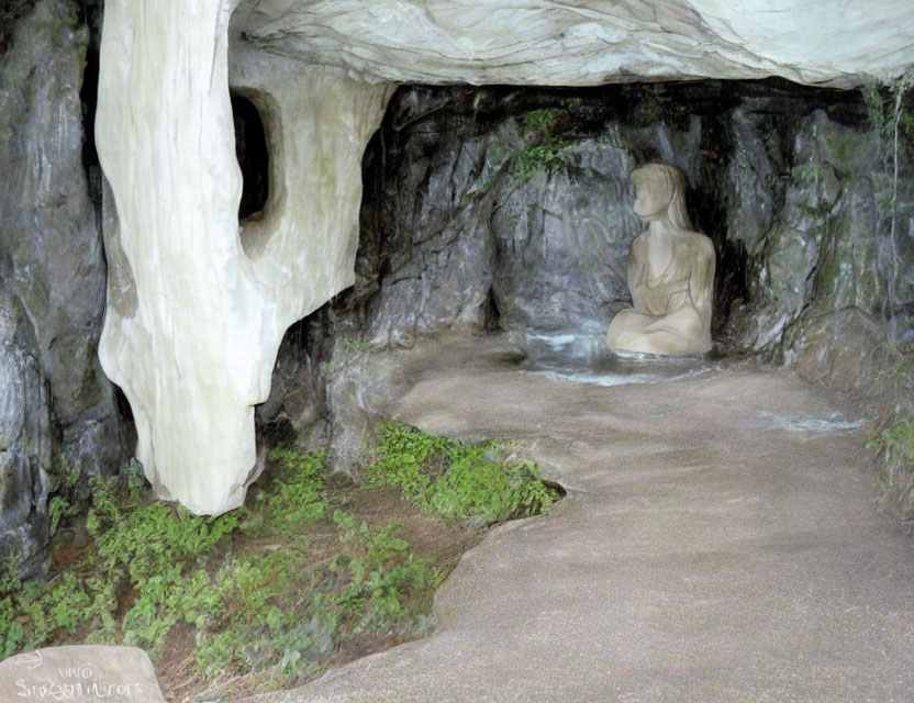 Meditating figure statue in cave-like setting with rocky walls