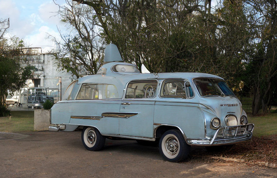 Vintage blue and white car with cylindrical rooftop attachment parked beside trees and building