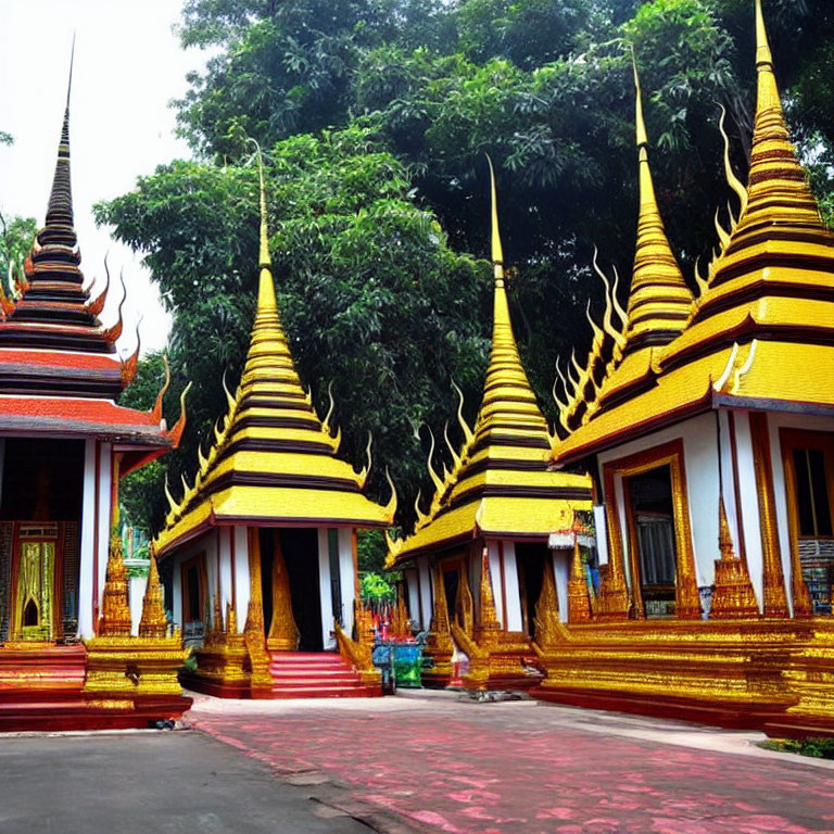 Traditional Thai-style pagodas with golden spires and red roofs amidst green trees under clear sky