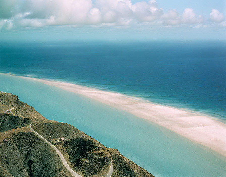 Scenic coastal road along cliff with tranquil sea and cloudy sky