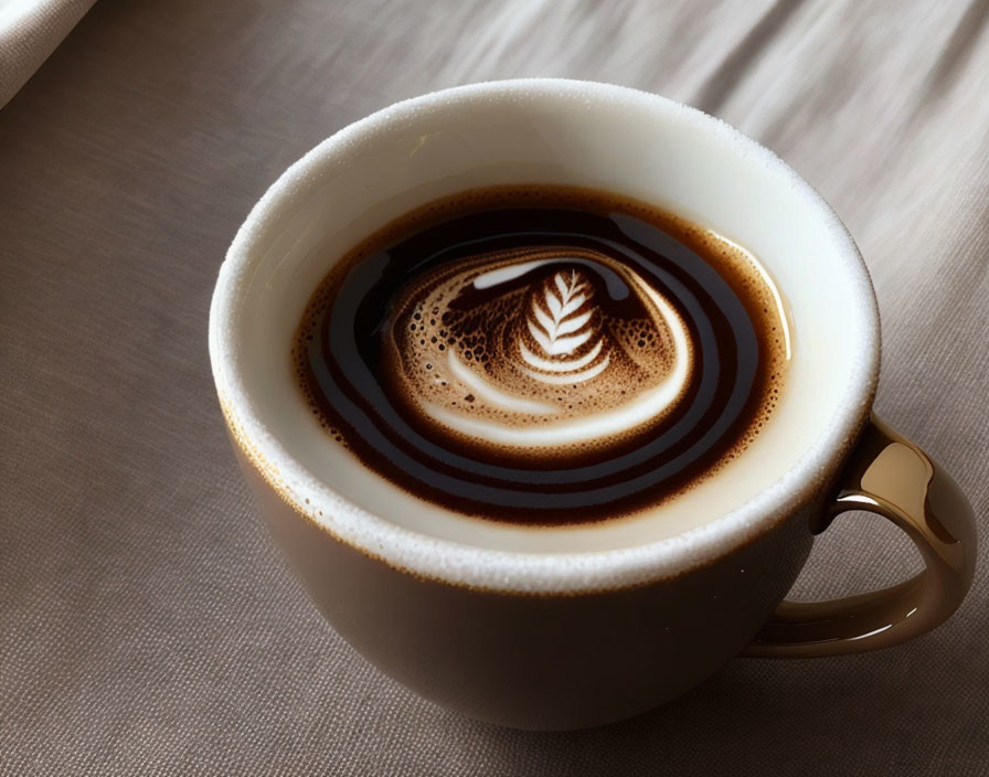 Detailed Latte Art Design on White Coffee Cup Resting on Wooden Table