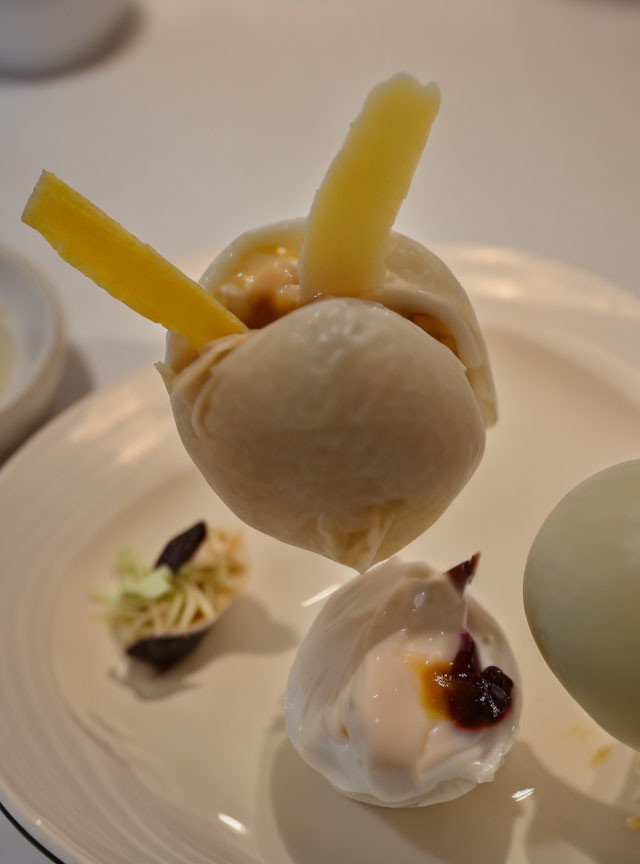 Steamed dumpling with visible filling and garnish on white plate