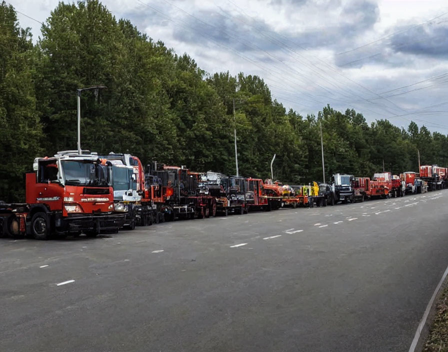 Red trucks and heavy machinery parked on roadside with trees