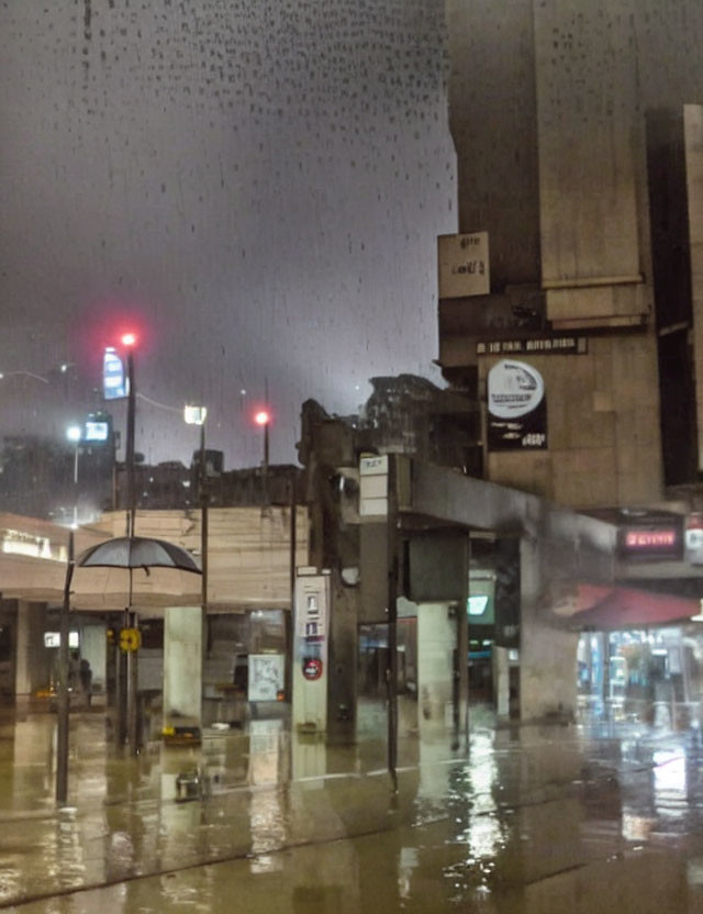 Rainy Evening Scene: Wet Streets, Red Traffic Lights, Silhouette at Bus Stop