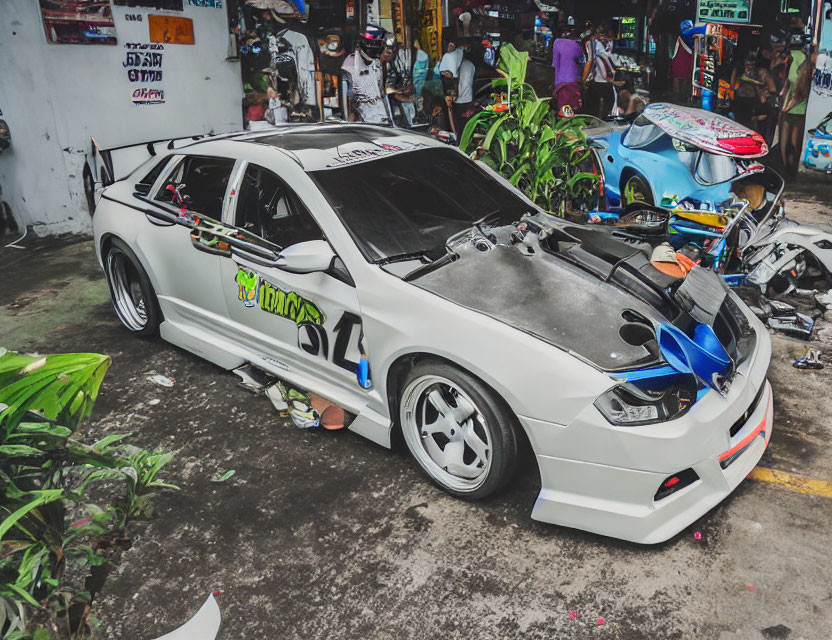 Custom white car with body kit and spoiler parked on urban street.