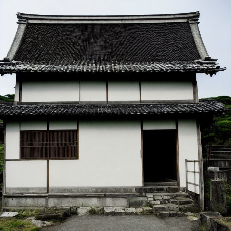 Traditional Japanese building with thatched roof and sliding doors under a cloudy sky