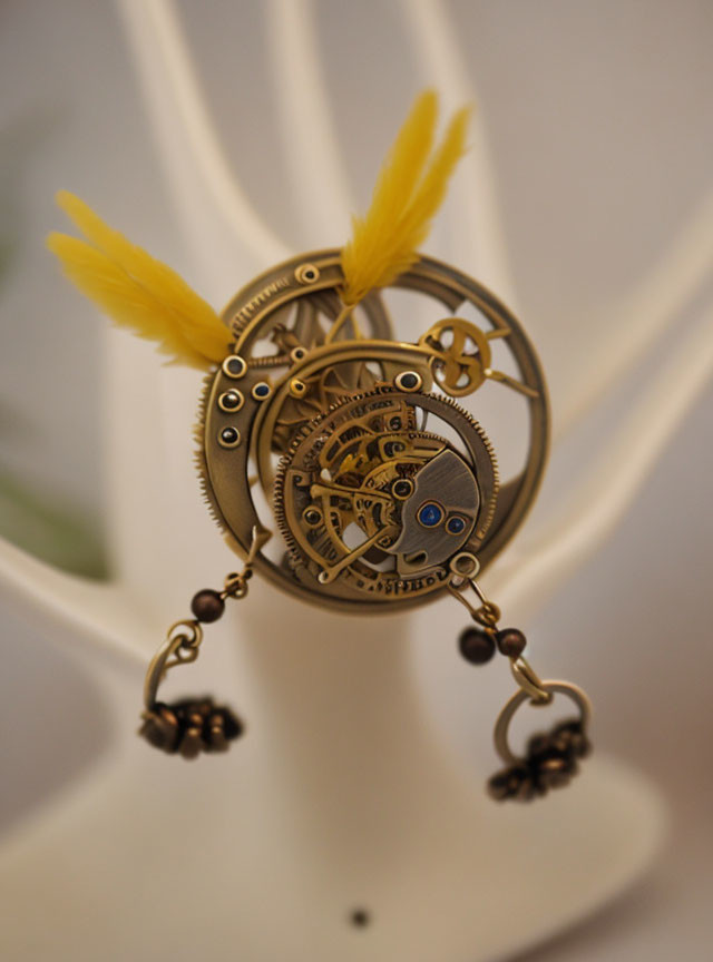 Steampunk Style Pendant with Gears, Cogs, and Feathers on White Stand