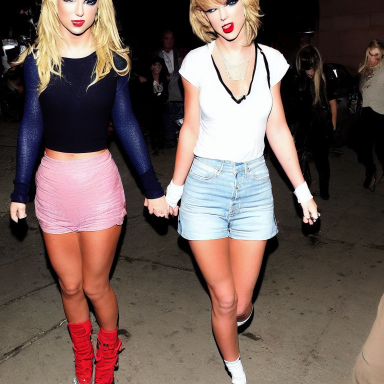 Two women in different outfits walking hand in hand with red lipstick.