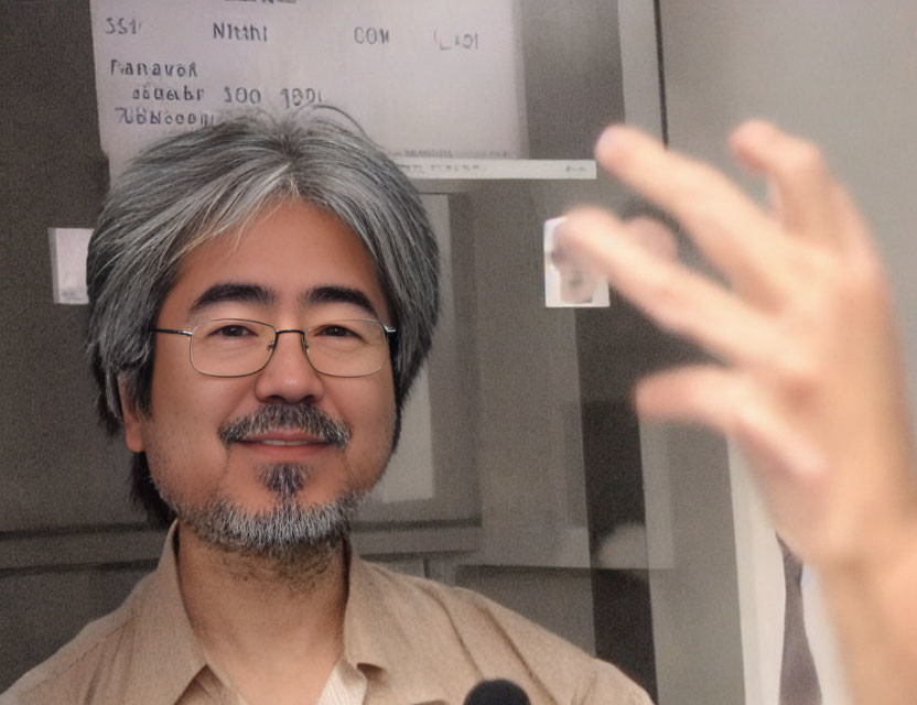 Salt-and-pepper Haired Man Smiling with Outstretched Hand in Foreground