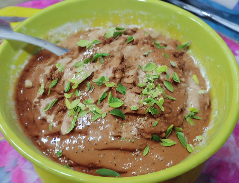 Brown paste with nuts and herbs in a bowl with a spoon