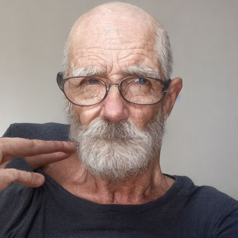 Gray-bearded elderly man in glasses and black T-shirt gesturing by face