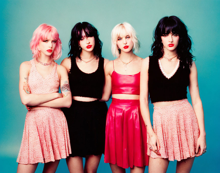 Four women with distinctive hairstyles and edgy fashion on light blue background