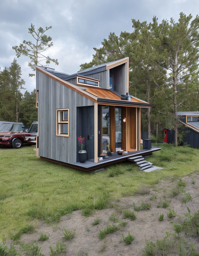 Modern tiny house with wooden accents and large windows in green surroundings with parked car under cloudy sky