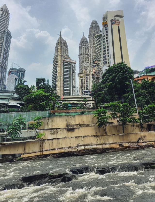 Turbulent river with moss-covered wall and modern skyscrapers under cloudy sky