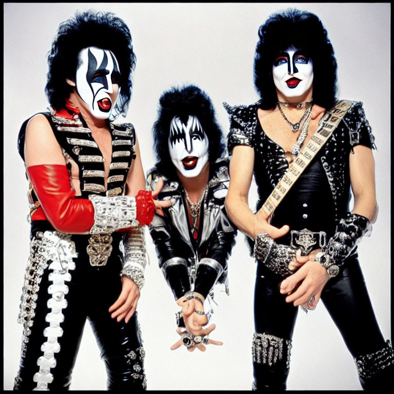 Group of three with black and white face makeup and rock costumes holding instruments