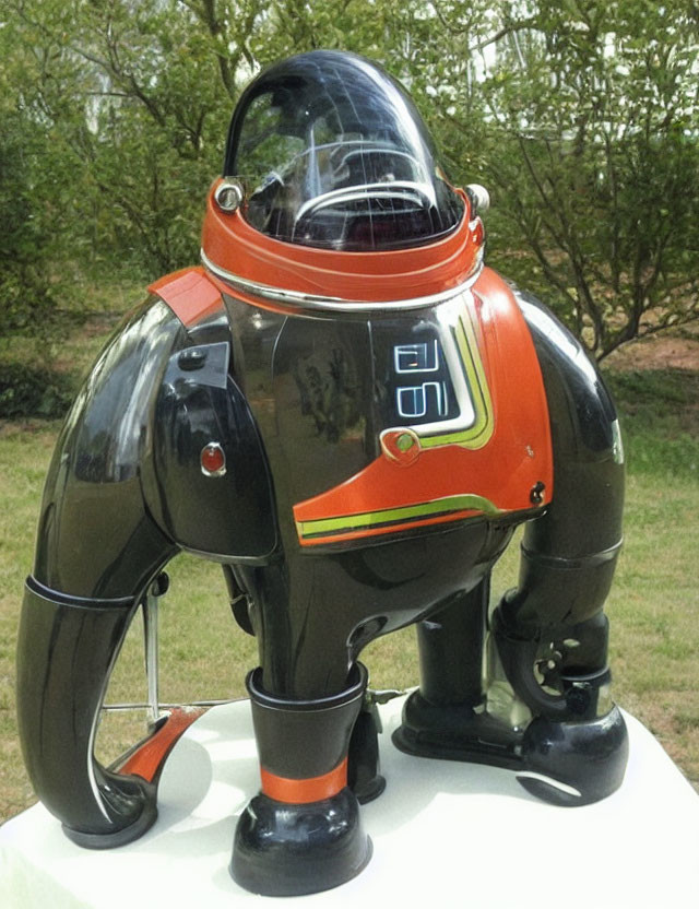 Vintage Black and Silver Robot with Transparent Dome Head and Orange Accents Displayed Outdoors