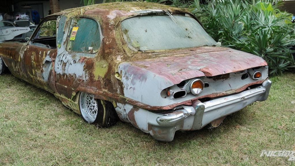 Rusted abandoned car covered in moss and plants in grassy area