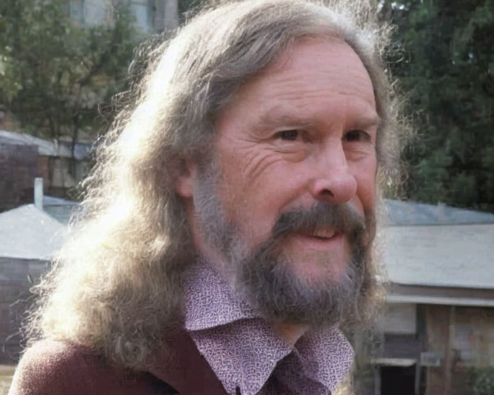 Smiling bearded man with long gray hair in urban setting