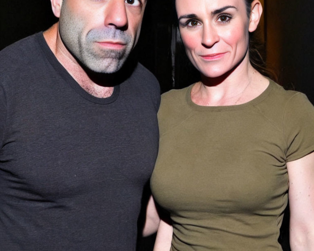 Bald man and woman in grey and olive green shirts posing together