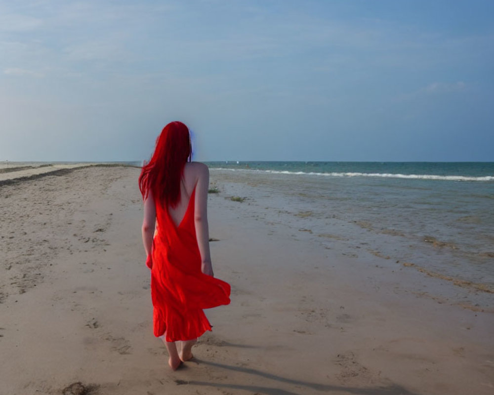 Red-haired woman in flowing dress on deserted beach gazes at horizon