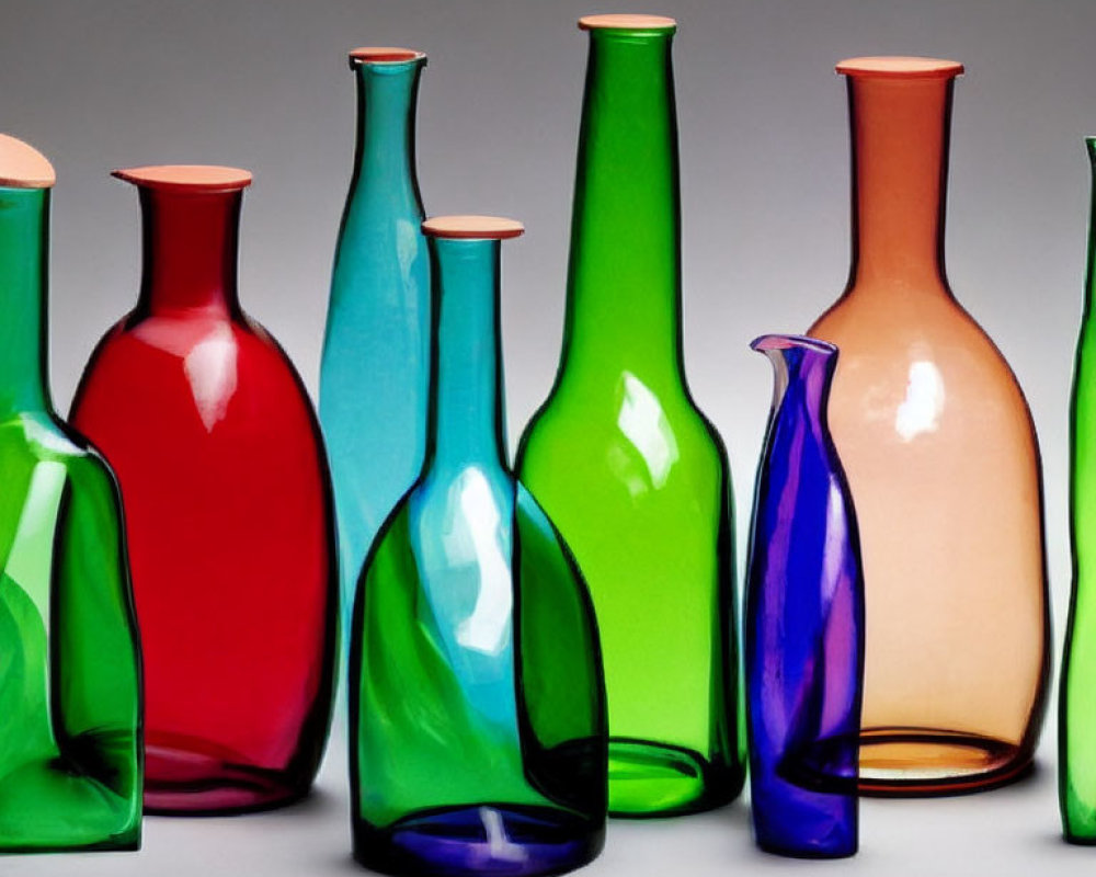 Vibrant glass bottle collection in green, blue, red, and peach on grey background