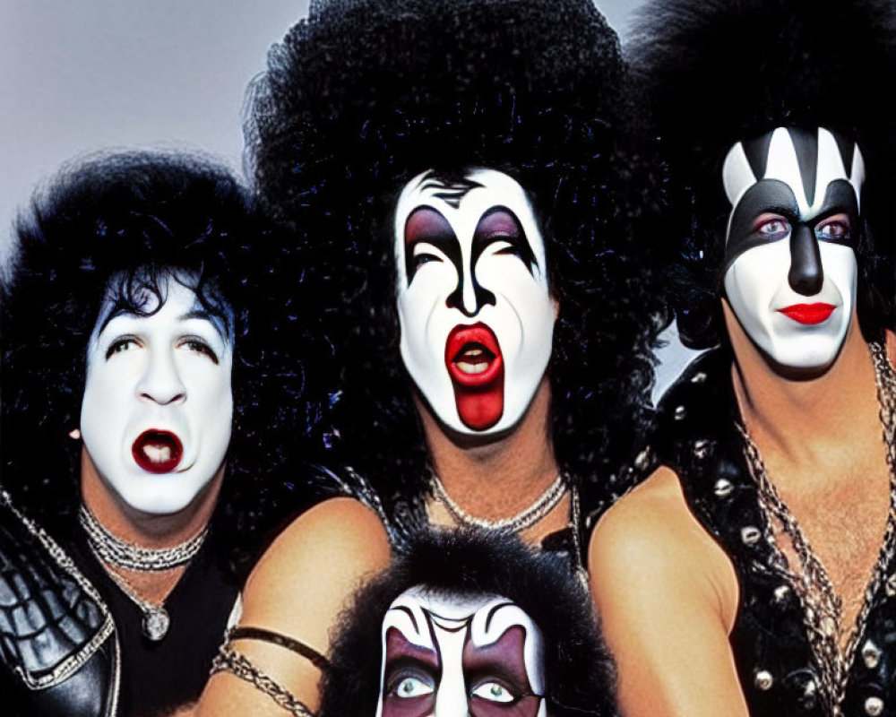 Four individuals with black and white face paint and flamboyant hair resembling rock band members.