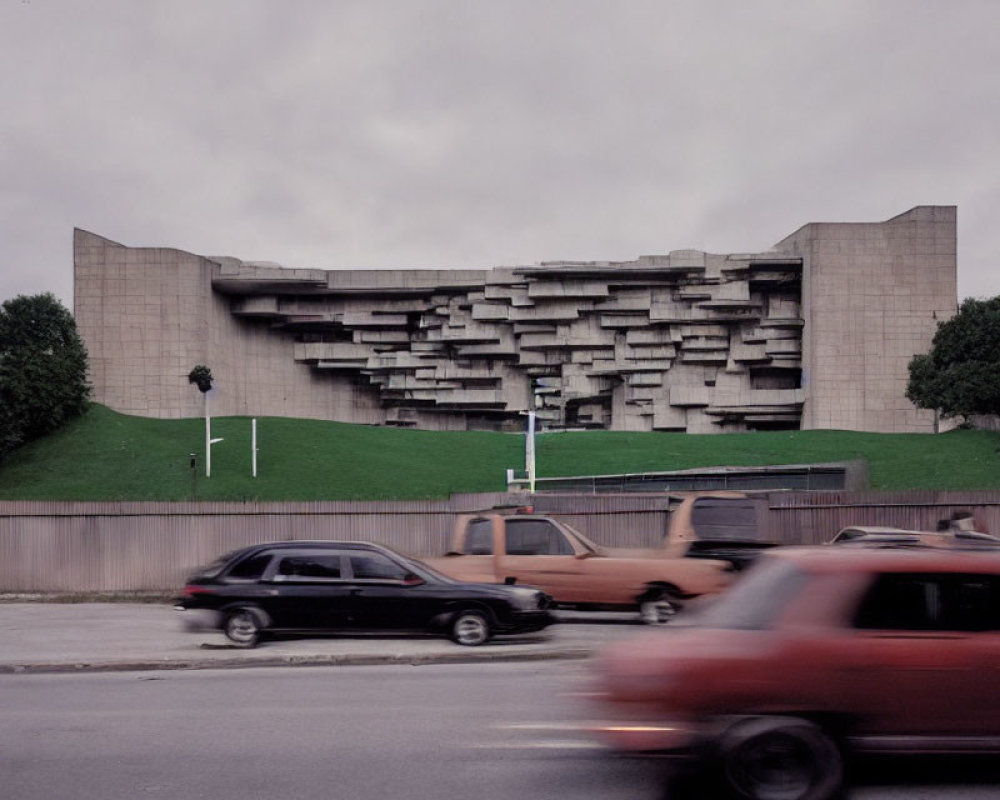 Brutalist-style building with stacked balconies and blurred cars in motion