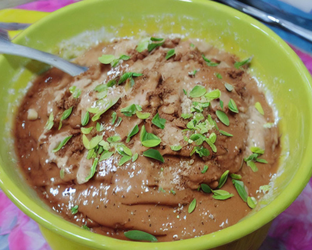 Brown paste with nuts and herbs in a bowl with a spoon