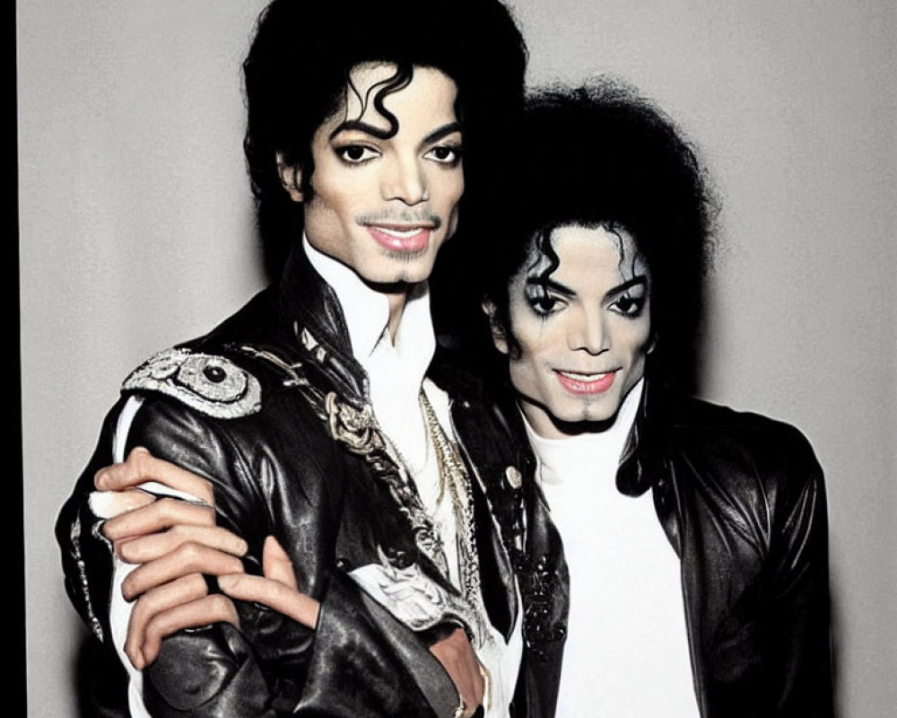 Two Michael Jackson look-alikes in matching black outfits and makeup against grey backdrop