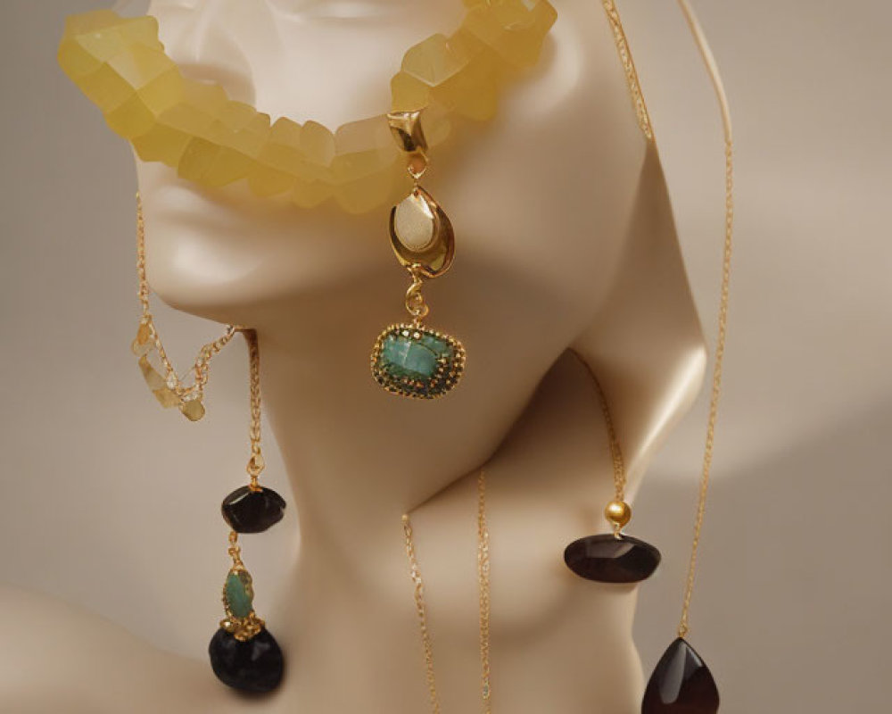 Mannequin head showcasing elegant gold jewelry with green and black gemstones