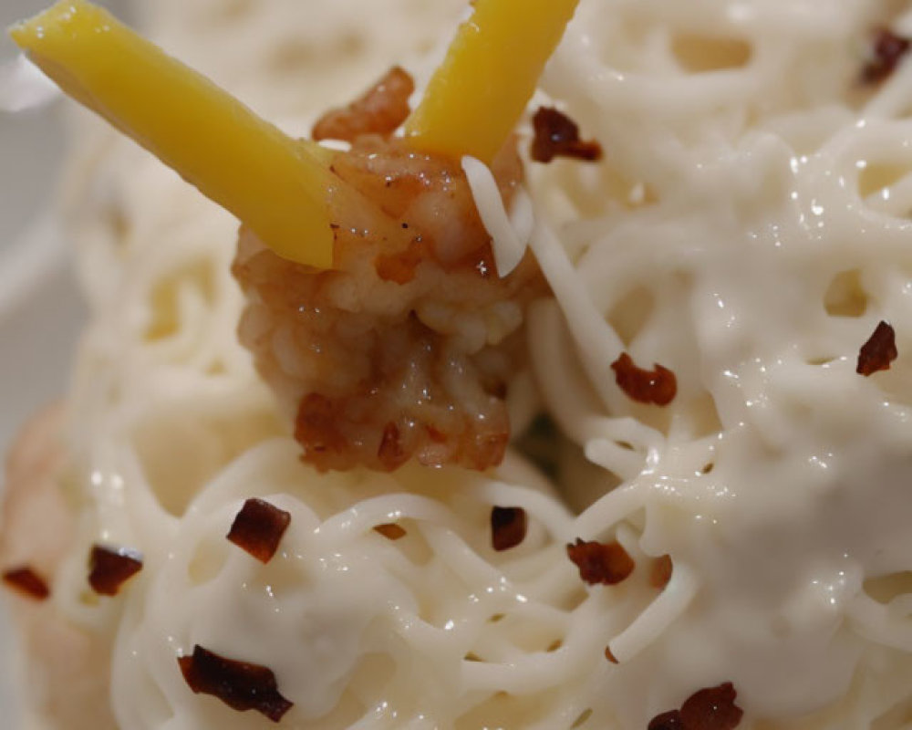 Creamy pasta dish with grated cheese, bacon bits, and yellow bell pepper slices