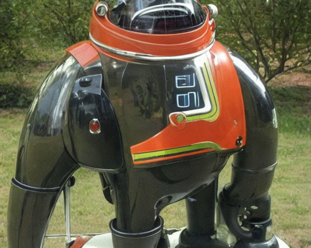 Vintage Black and Silver Robot with Transparent Dome Head and Orange Accents Displayed Outdoors